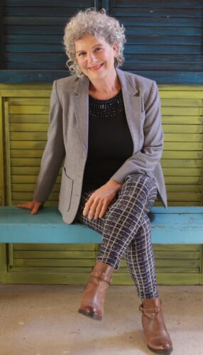 תמונת מיכל רוזן יושבת עם ז'קט אפור